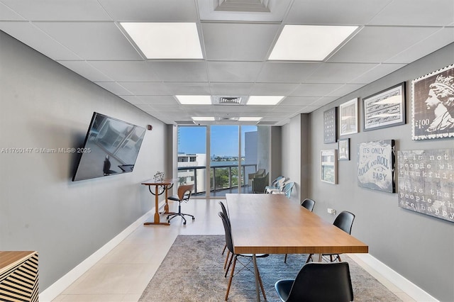 office space featuring tile patterned floors, visible vents, baseboards, and a drop ceiling