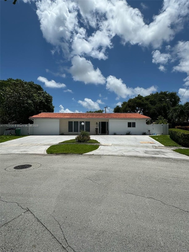 view of front of home with a tiled roof, driveway, and fence