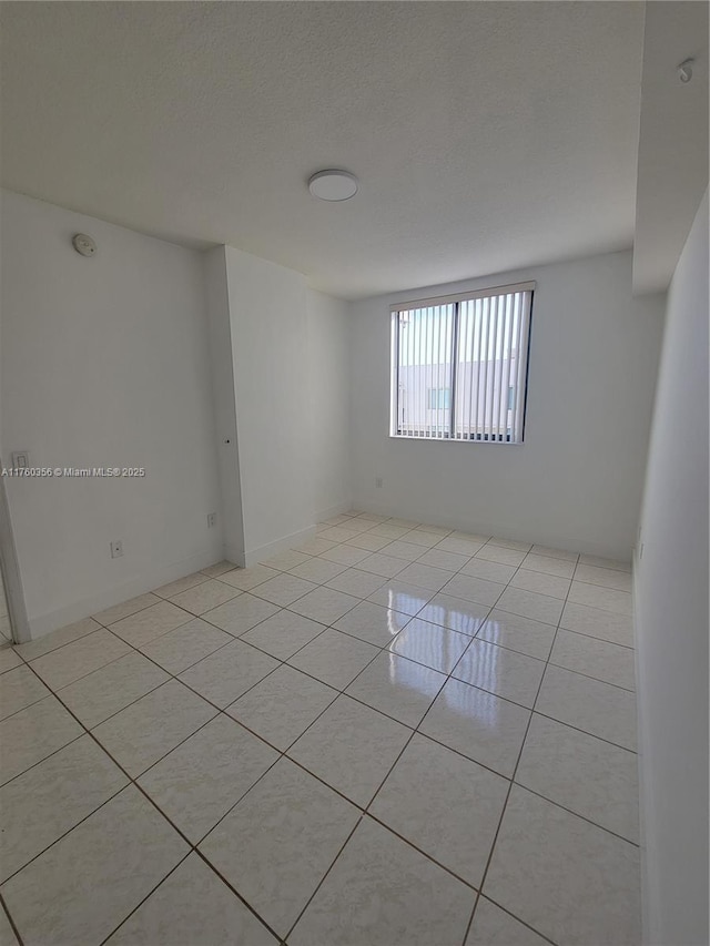 unfurnished room with light tile patterned floors and a textured ceiling