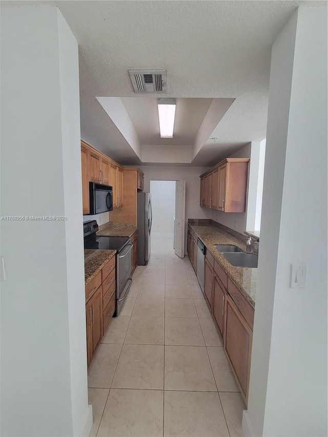 kitchen featuring visible vents, a sink, a tray ceiling, a textured ceiling, and stainless steel appliances