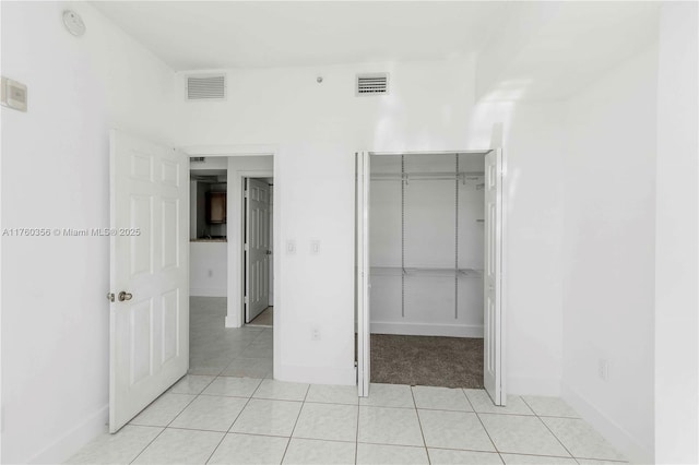 unfurnished bedroom with visible vents, baseboards, light tile patterned floors, and a closet