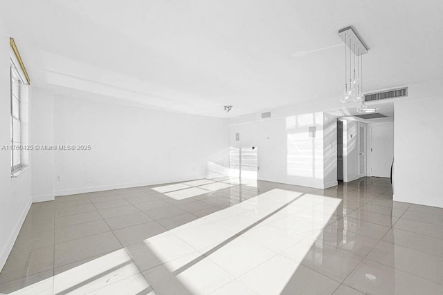 tiled empty room with baseboards and visible vents