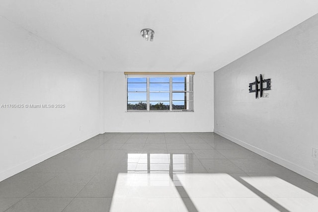 tiled spare room featuring baseboards