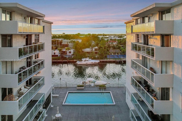 pool at dusk featuring a water view