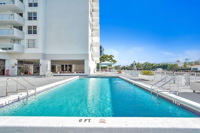 community pool with a patio and fence