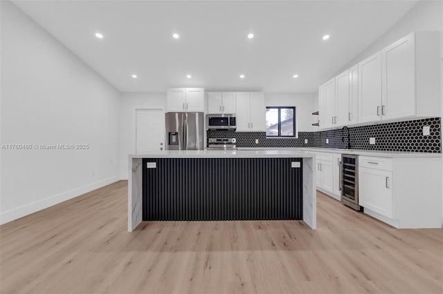 531 NE 175th Ter, North Miami Beach, FL 33162 - kitchen featuring appliances with stainless steel finishes, beverage cooler, white cabinets, light wood-type flooring, and a kitchen island