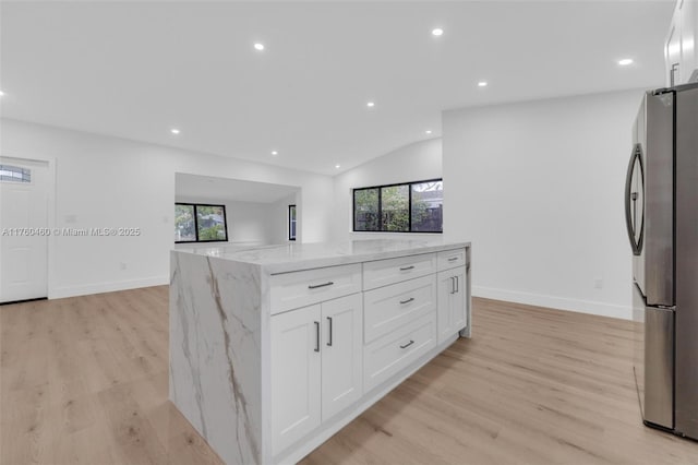 531 NE 175th Ter, North Miami Beach, FL 33162 - kitchen featuring freestanding refrigerator, vaulted ceiling, light stone counters, light wood-style floors, and white cabinets