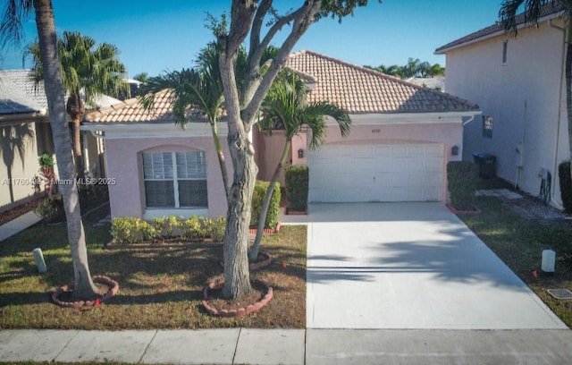 mediterranean / spanish-style house with concrete driveway, a tiled roof, an attached garage, and stucco siding