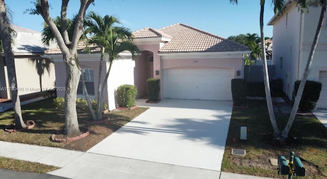 view of front of home with stucco siding, an attached garage, a tile roof, and concrete driveway