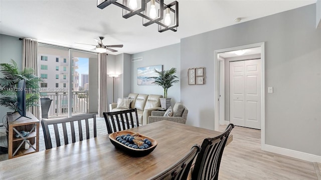 dining space featuring light wood finished floors, a ceiling fan, a wall of windows, and baseboards