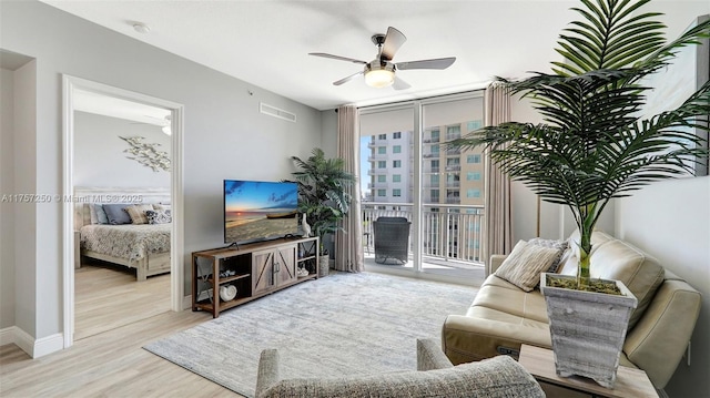 living room featuring a wall of windows, wood finished floors, baseboards, visible vents, and ceiling fan