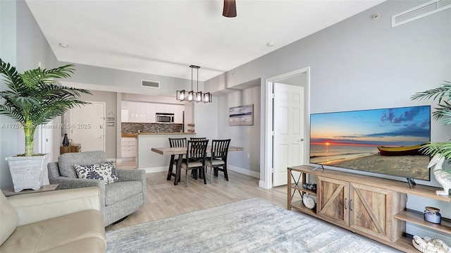 living room with visible vents, baseboards, and light wood-style floors