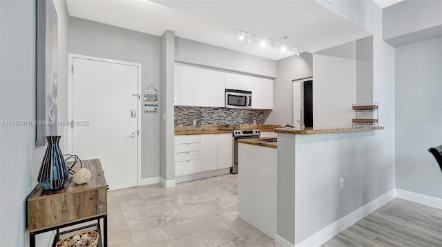 kitchen featuring white cabinetry, decorative backsplash, baseboards, and appliances with stainless steel finishes