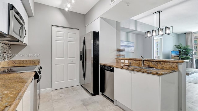 kitchen with a sink, stone countertops, stainless steel appliances, a peninsula, and white cabinets