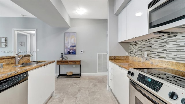 kitchen featuring visible vents, a sink, white cabinetry, stainless steel appliances, and decorative backsplash