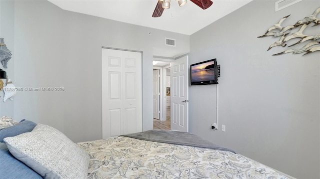 bedroom featuring lofted ceiling, a ceiling fan, visible vents, and a closet