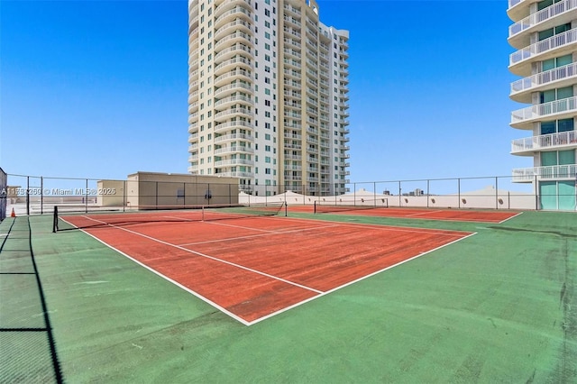 view of tennis court with community basketball court and fence