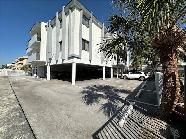 view of building exterior featuring covered and uncovered parking