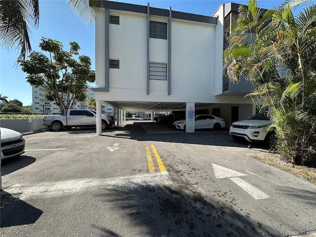 view of building exterior featuring covered and uncovered parking