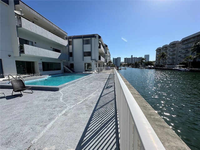 community pool with a city view, a patio area, and a water view