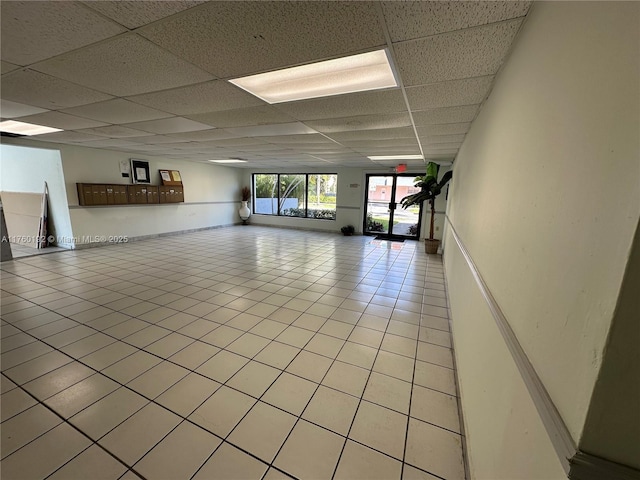 interior space with light tile patterned flooring and a paneled ceiling