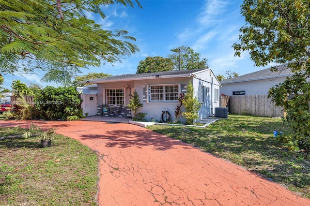 view of front of house featuring central AC unit, fence, a front yard, and stucco siding