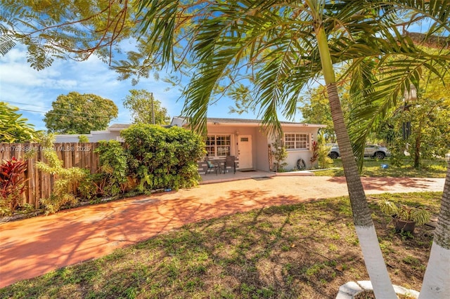 view of front of property with stucco siding, a patio, and fence