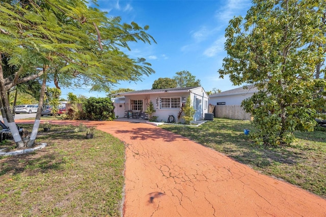 ranch-style house featuring a front yard, central AC unit, fence, stucco siding, and concrete driveway