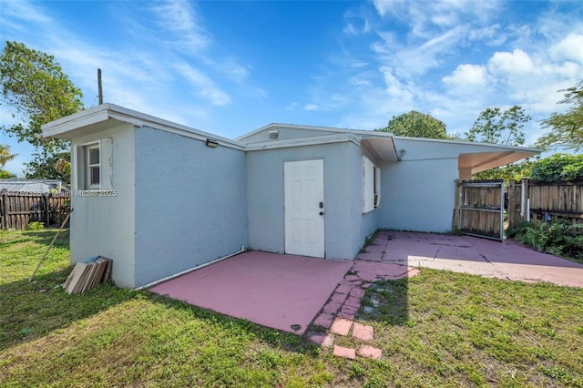 back of house featuring fence, a patio area, a lawn, and stucco siding