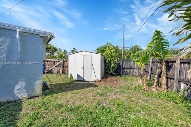 view of yard with an outdoor structure, a fenced backyard, and a shed