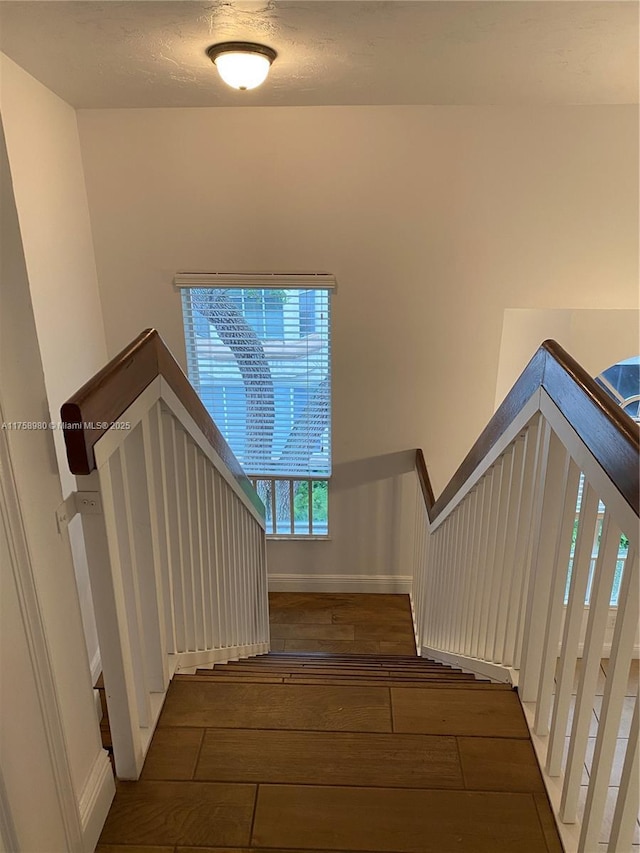 stairway featuring a textured ceiling, baseboards, and wood finished floors