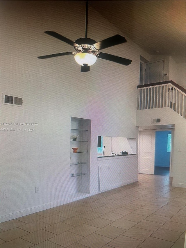 spare room with visible vents, a high ceiling, and ceiling fan