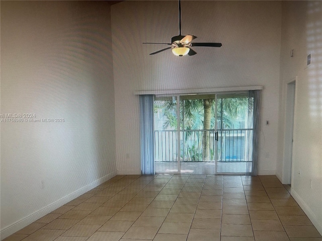 unfurnished room featuring light tile patterned floors, baseboards, a towering ceiling, and a ceiling fan