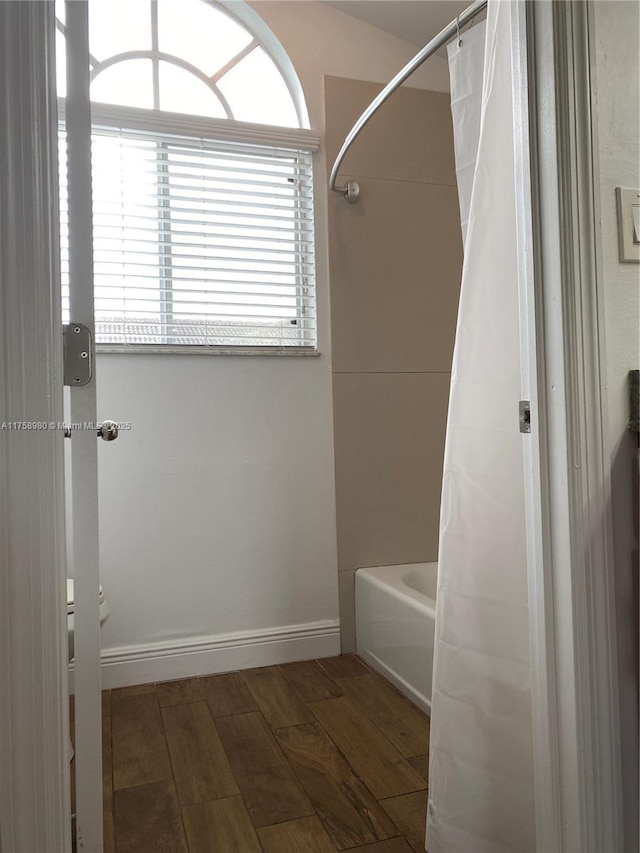 bathroom featuring shower / bath combo with shower curtain, baseboards, and wood finished floors