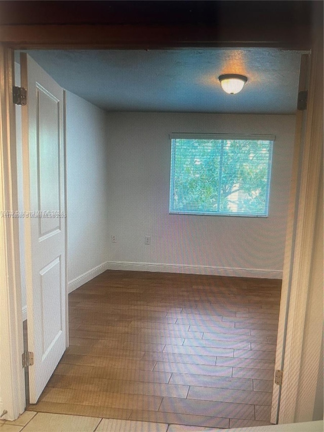 empty room with baseboards and wood finished floors