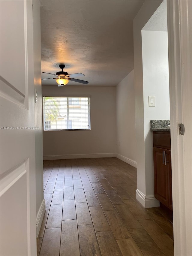 spare room featuring baseboards, ceiling fan, and wood finished floors