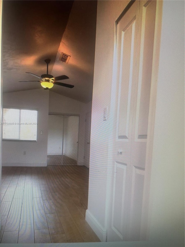 unfurnished room featuring vaulted ceiling, a ceiling fan, visible vents, and wood finished floors