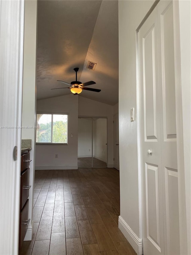 interior space featuring visible vents, baseboards, ceiling fan, vaulted ceiling, and wood finished floors