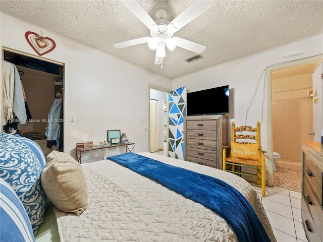 bedroom featuring light tile patterned floors, visible vents, a textured ceiling, and a ceiling fan