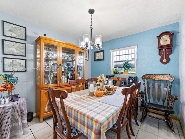 dining room with light tile patterned flooring, a textured wall, baseboards, and a chandelier