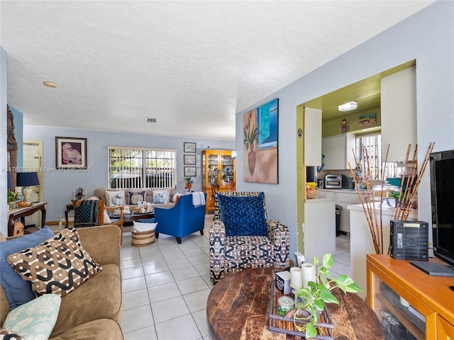 living room featuring light tile patterned flooring, visible vents, and a textured ceiling