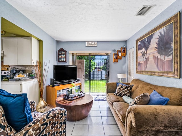 living area featuring visible vents, a textured ceiling, and light tile patterned flooring