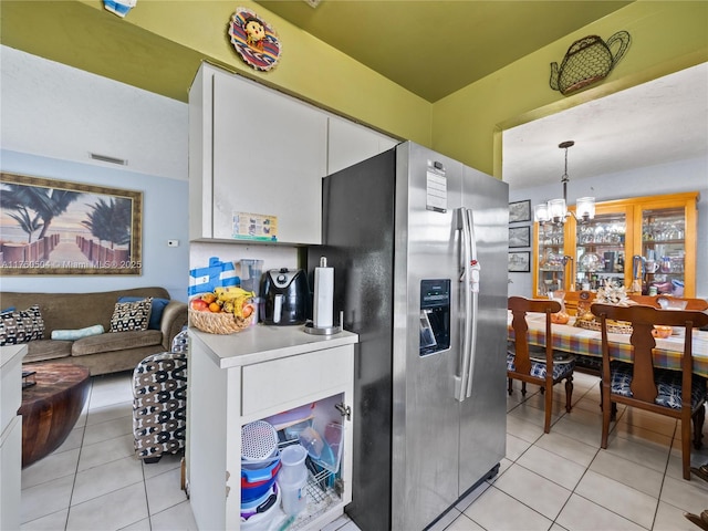 kitchen featuring visible vents, light tile patterned floors, an inviting chandelier, stainless steel refrigerator with ice dispenser, and white cabinetry