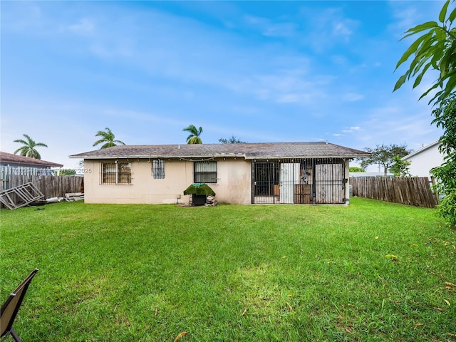 rear view of property with a yard, a fenced backyard, and stucco siding