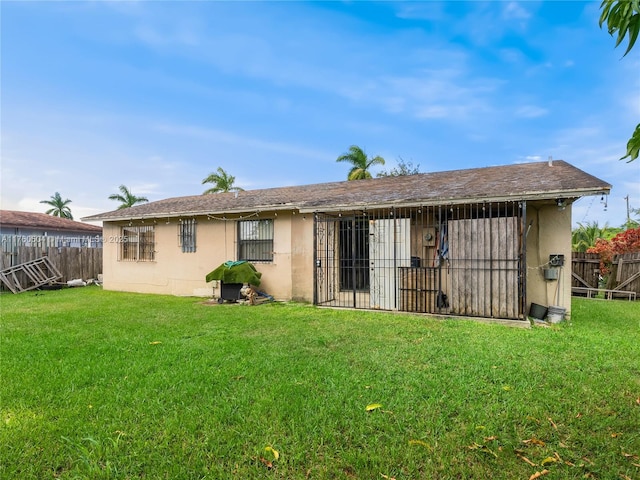 back of property with fence private yard, a lawn, and stucco siding