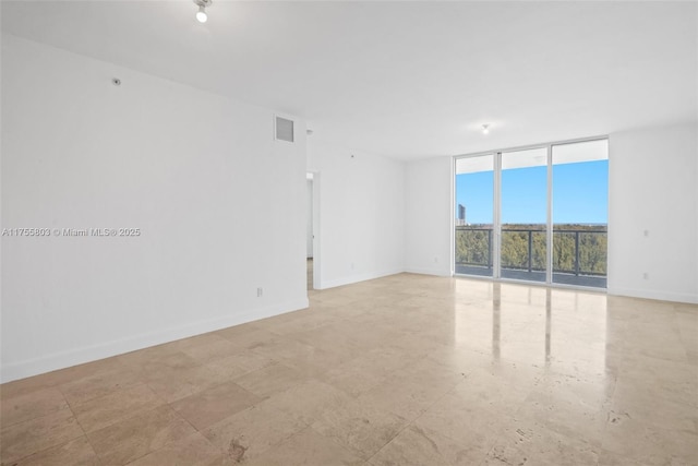 spare room featuring visible vents, baseboards, and expansive windows