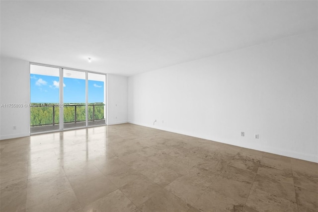 spare room featuring baseboards and floor to ceiling windows