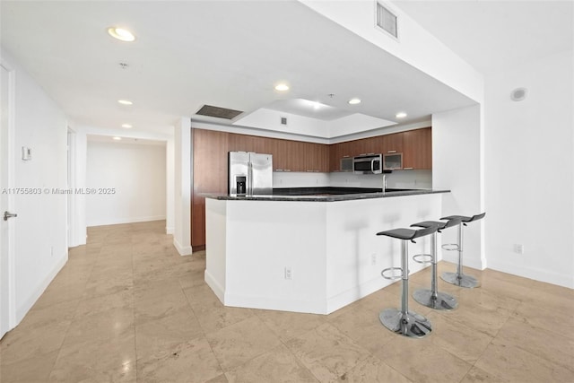 kitchen with dark countertops, visible vents, appliances with stainless steel finishes, and a breakfast bar area