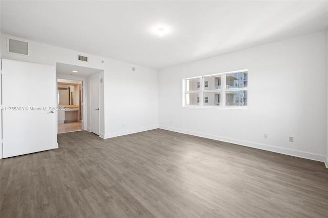 empty room featuring visible vents, baseboards, and wood finished floors