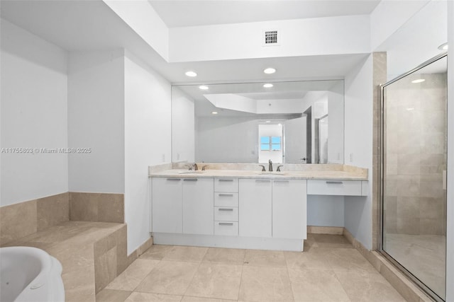 bathroom with a garden tub, double vanity, visible vents, and a sink